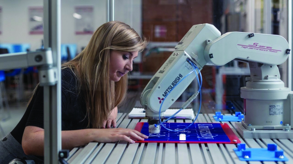 a design engineer who is female works with a machine in a workshop