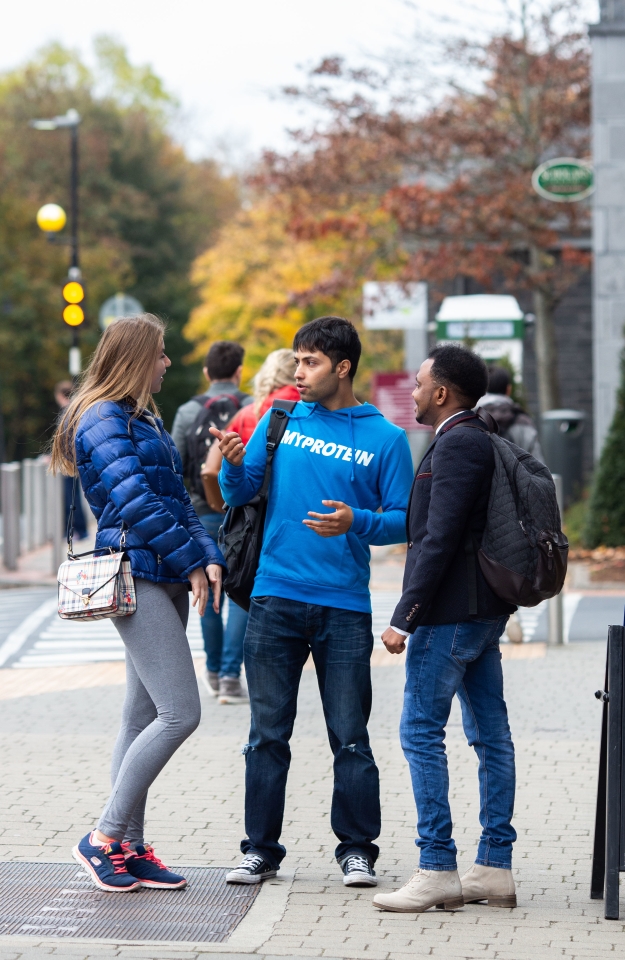 three students standing and talking outside