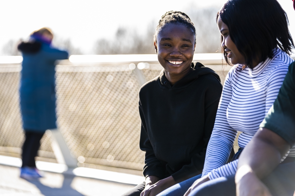 Two female students smiling and talking, while sitting on the UL Living Bridge